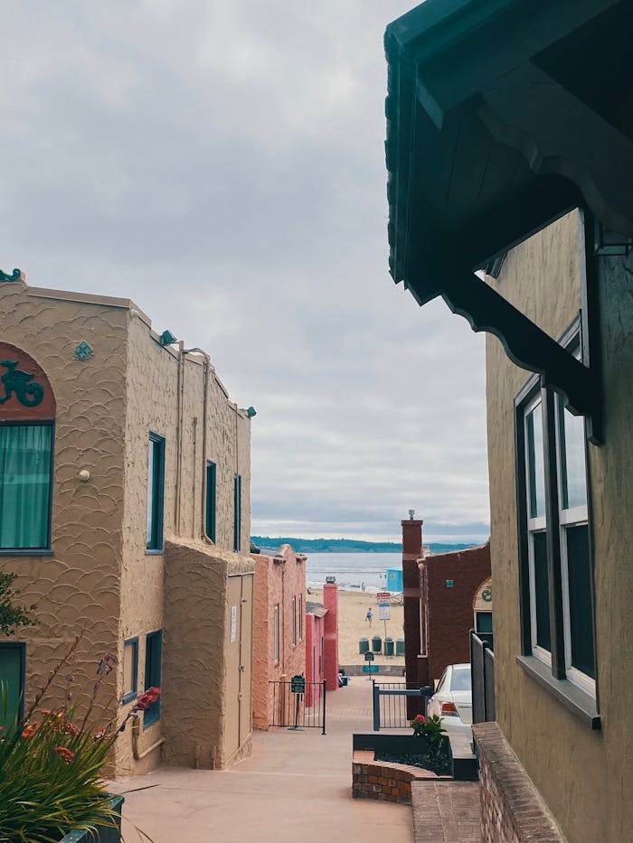 View through vibrant Capitola alleyway towards a beach with colorful houses in California.